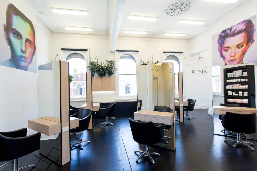 Cream Melbourne bright styling floor — pop-art faces, Redken product wall, arched windows, chandelier